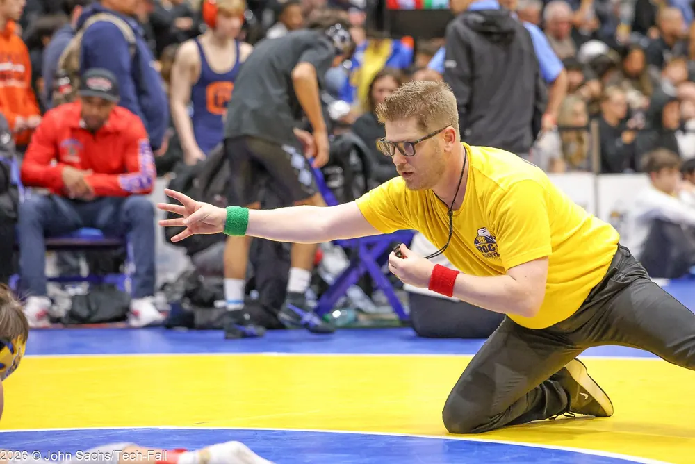An official lunges and signals during a match.